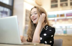 Woman in Black and White Polka Dots Dress Sitting by the Table Using Macbook